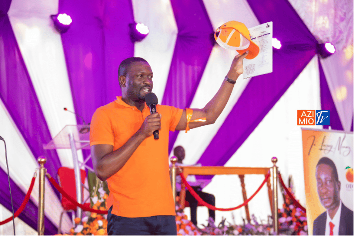 Nairobi Senator Edwin Sifuna raises an orange cap and document at an event while speaking, relevant to his potential Sifuna 2027 Presidential Bid.