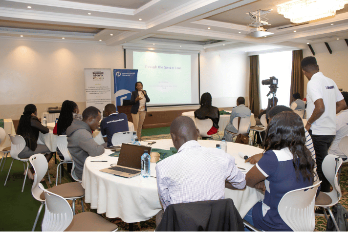 Journalists listening to a presentation titled Through the Gender Lens projected on screen during an AMWIK training workshop.