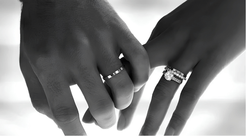 Black and white shot of a married couple holding hands with wedding rings, showing how childhood traumas and modern marriage dynamics interact.