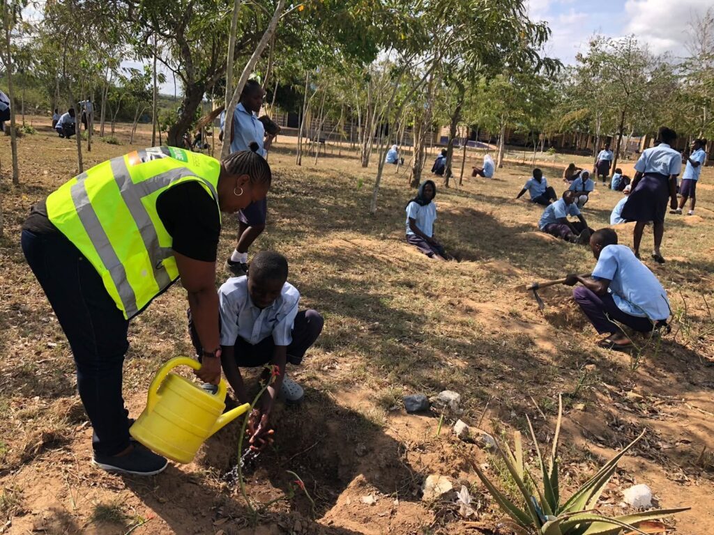 NACADA officer assisting Kirinyaga pupils in watering planted trees on school grounds