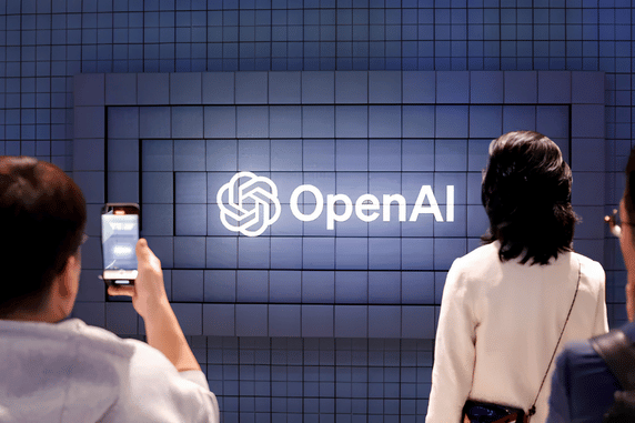 Visitors taking photos of illuminated OpenAI logo display wall at an event