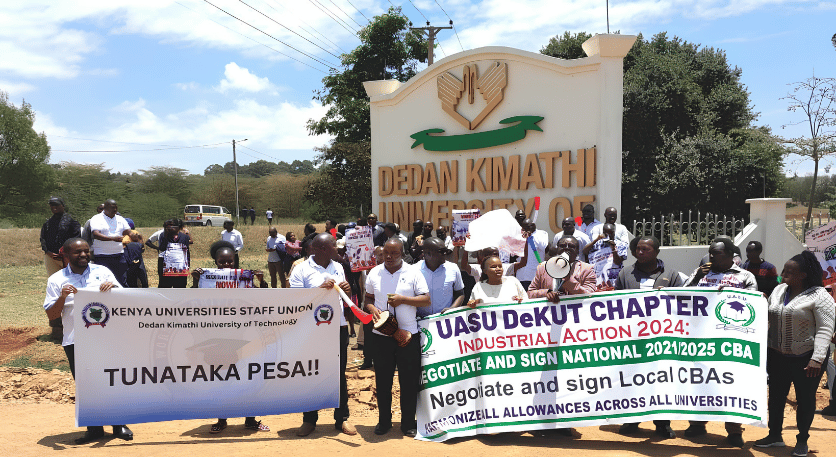 Striking public university lecturers and KUSU representatives march with protest banners outside Dedan Kimathi University of Technology.