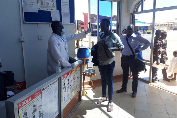 Health official screening a traveler for fever and Ebola symptoms at a border point of entry