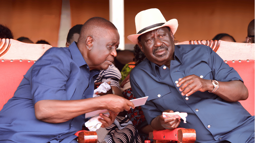 Dr. Oburu Odinga leaning in to consult with his late brother Raila Odinga during a public event.