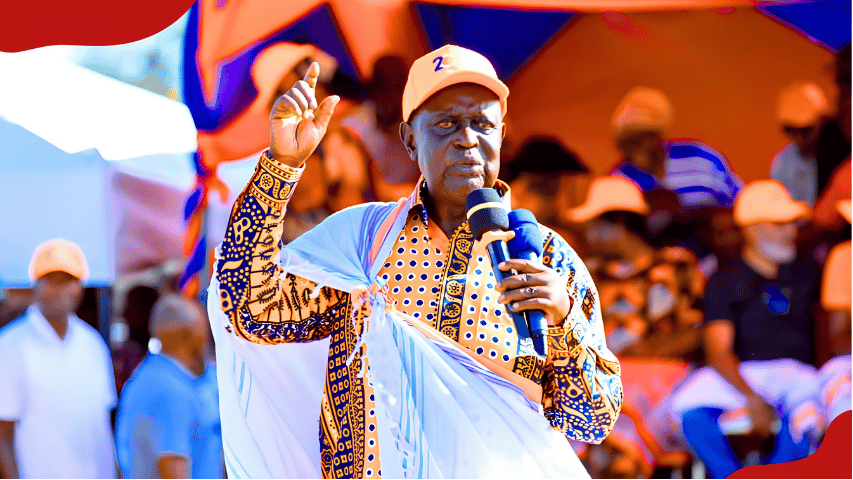 Dr. Oburu Odinga wearing an orange baseball cap and traditional patterned attire, holding microphones and gesturing while addressing a political gathering.