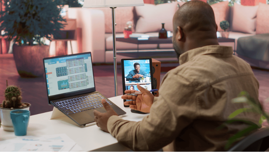 A professional conducting a virtual video conference meeting on a tablet next to a laptop displaying data, representing global remote jobs and digital collaboration